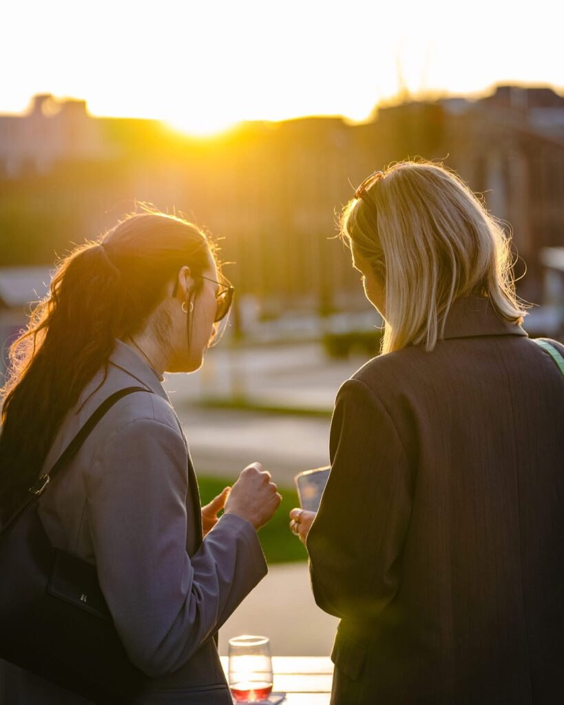 Gasten in gesprek bij zonsondergang op het dek